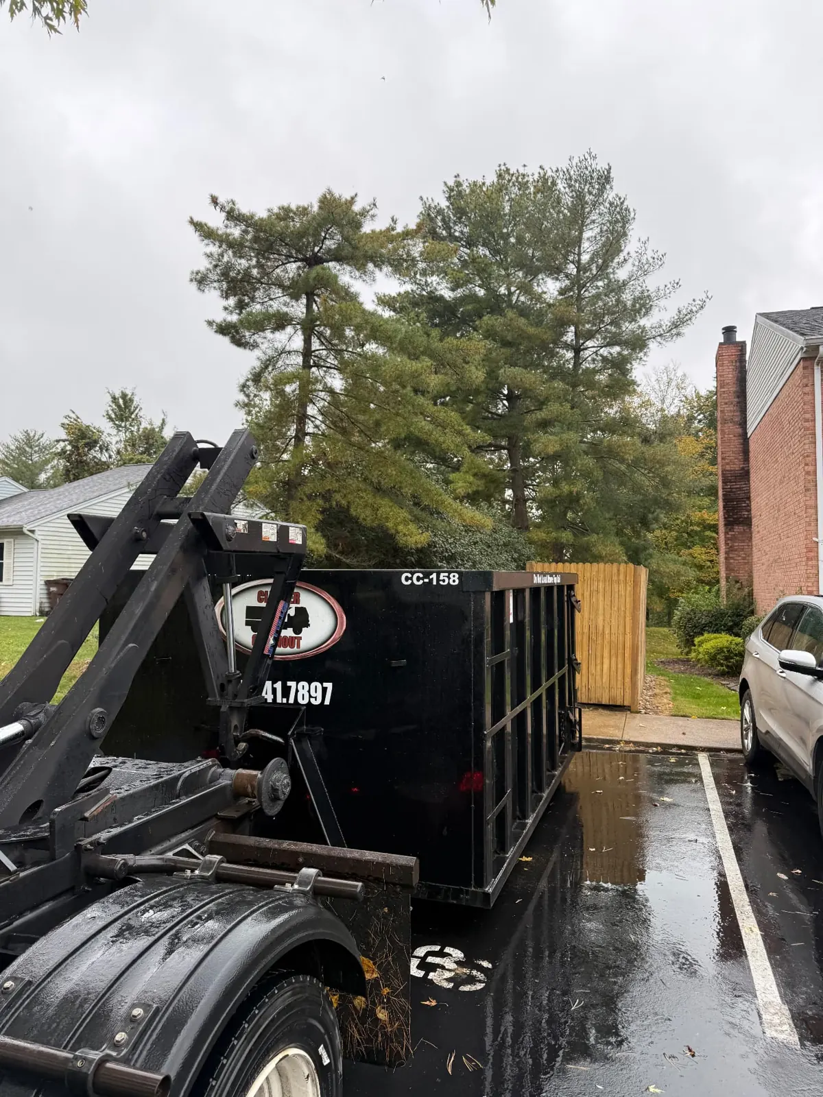 Clutter Cleanout 15 yard dumpster CC-158 with the roll-off truck in a paved parking area beside homes in Anderson Township, OH