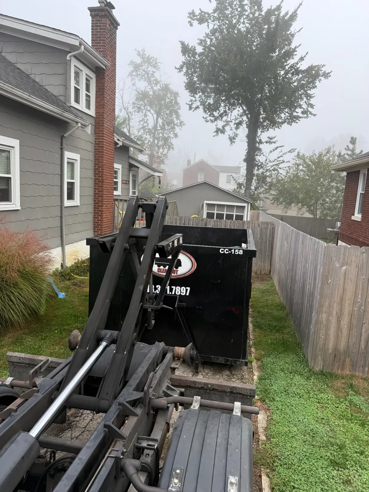 Clutter Cleanout 15 yard dumpster CC-158 with the roll-off truck beside a home in Montgomery, OH