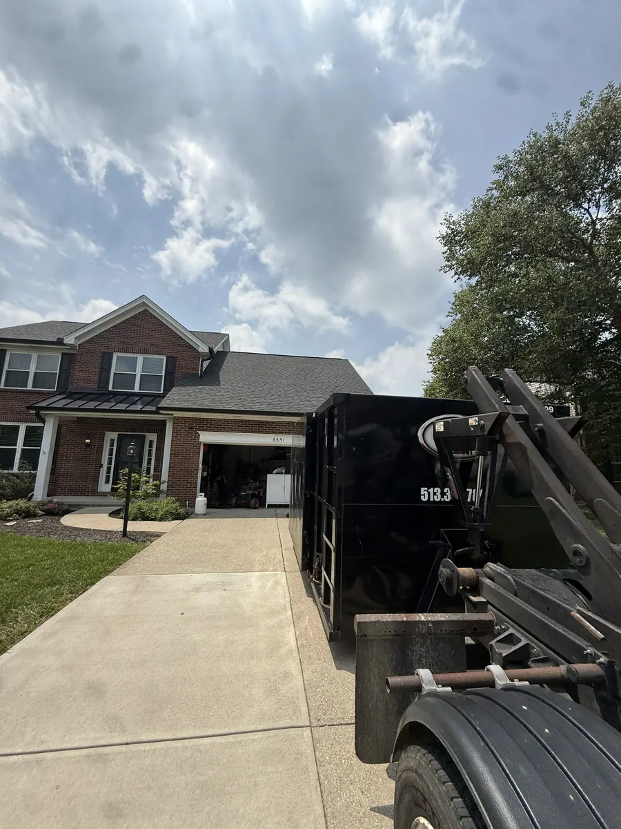 Clutter Cleanout 20 yard dumpster being delivered to a brick two-story home driveway in Loveland, OH