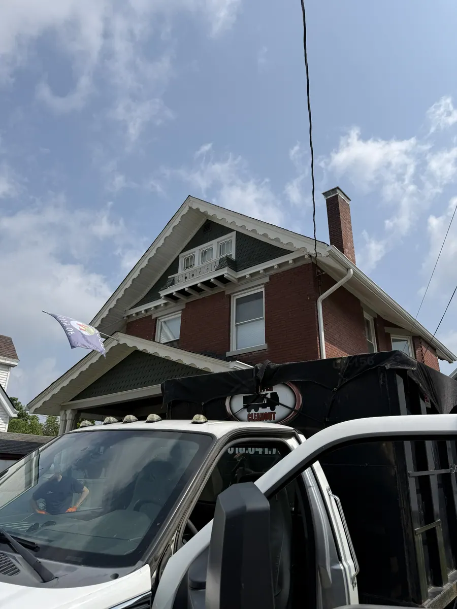Clutter Cleanout truck delivering a tarped 15 yard dumpster CC-156 in front of a brick Craftsman home in Oakley, Cincinnati OH