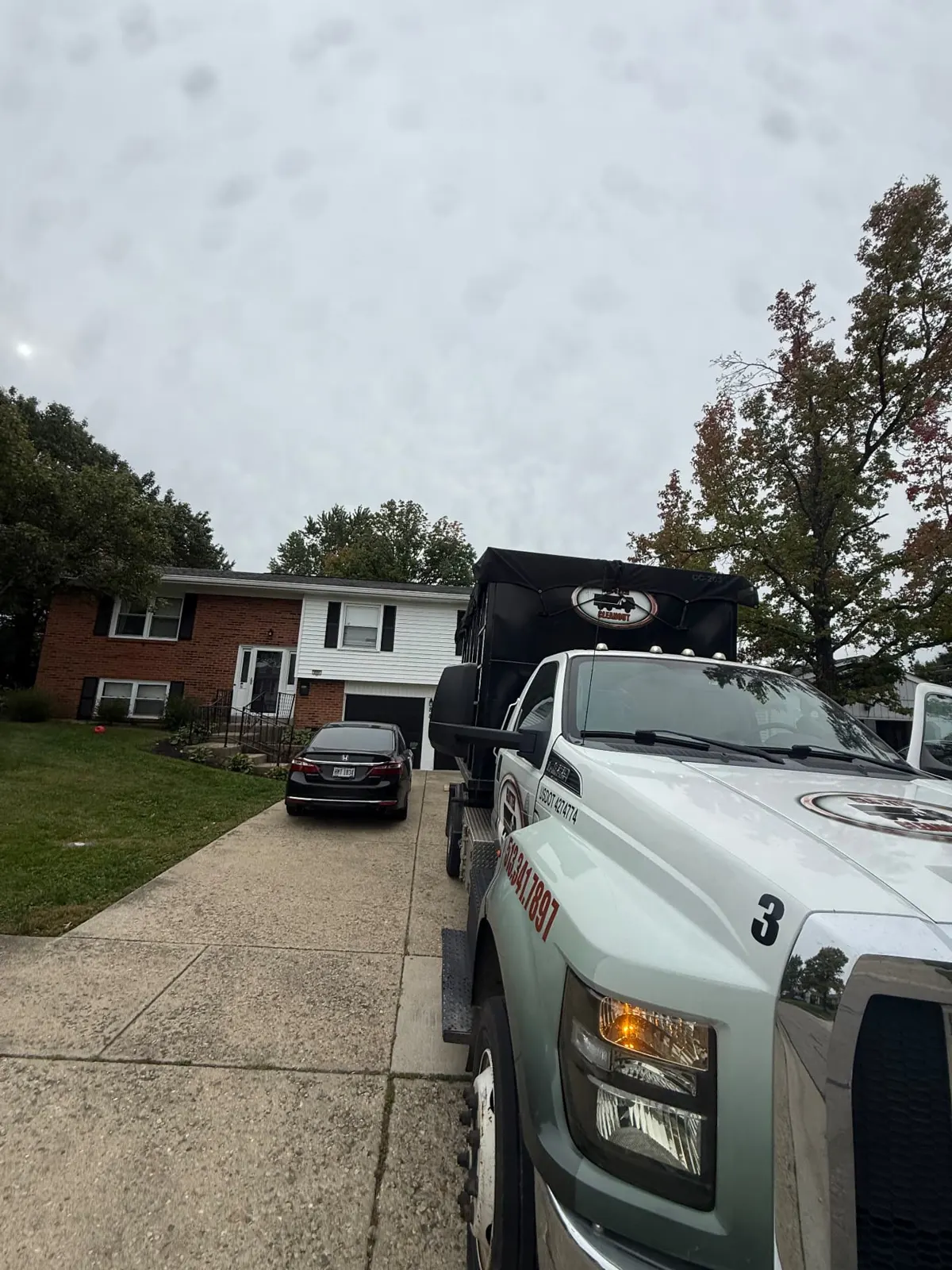 Clutter Cleanout roll-off truck carrying a tarped 20 yard dumpster at a residential driveway in West Chester, OH