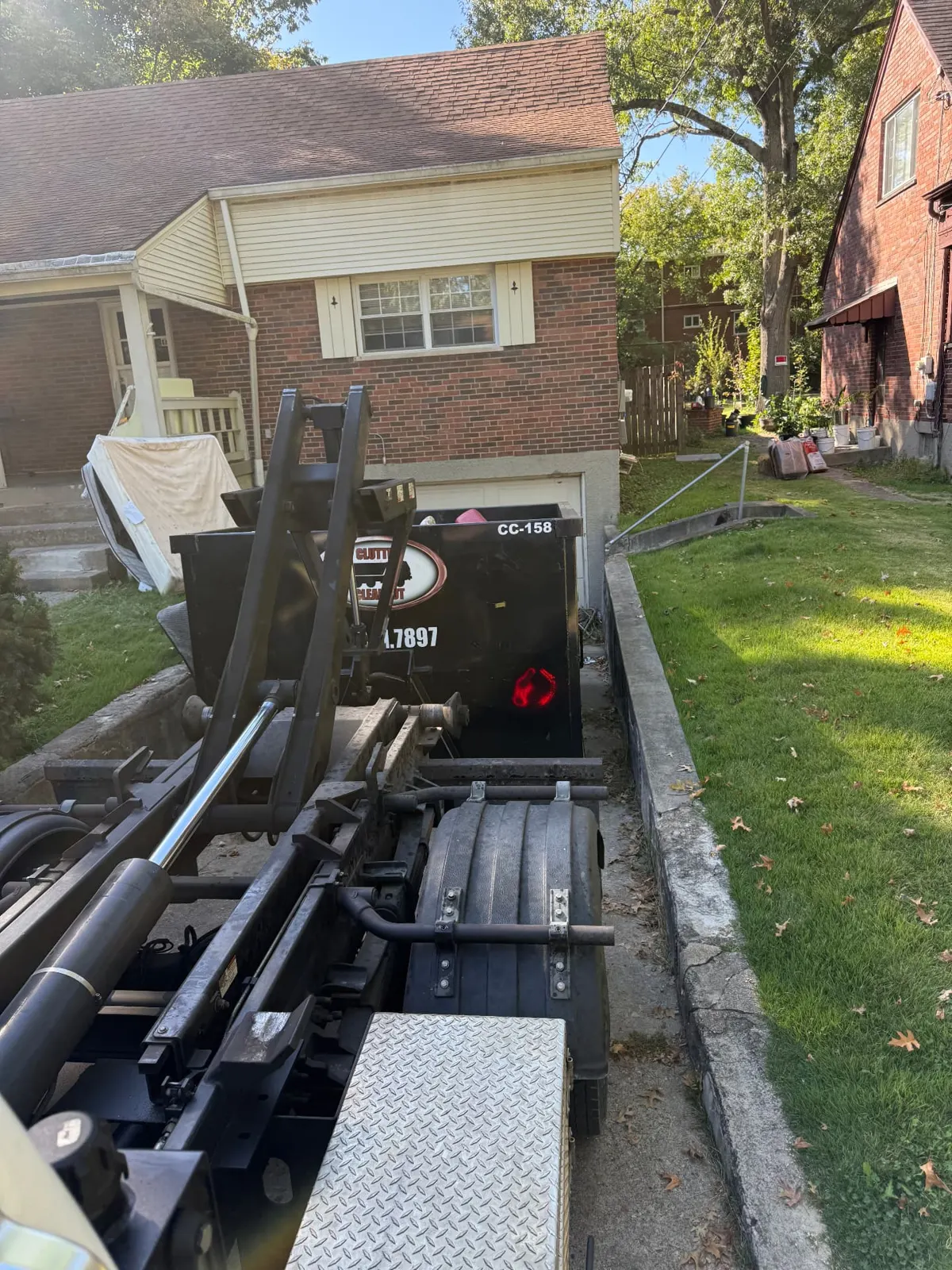 Clutter Cleanout 15 yard dumpster CC-158 with the roll-off truck in a narrow residential driveway in Cincinnati, OH