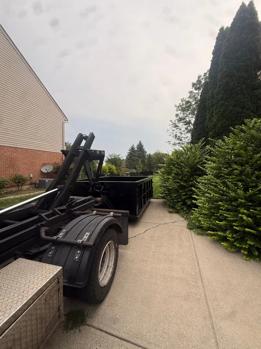 Clutter Cleanout roll-off truck delivering a 10 yard dumpster to a driveway beside a home in Loveland, OH