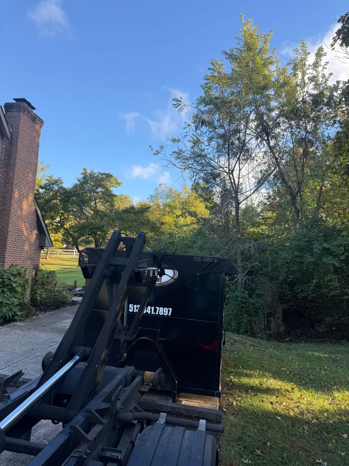 Clutter Cleanout tarped 20 yard dumpster CC-2014 with the roll-off truck on a tree-lined driveway in West Chester, OH