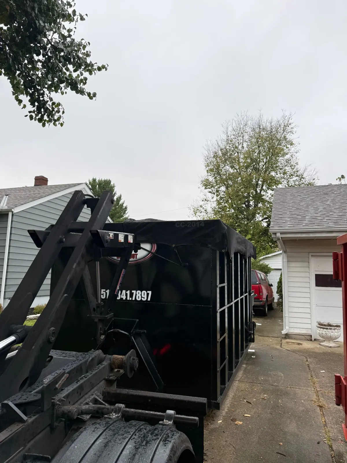 Clutter Cleanout tarped 20 yard dumpster CC-2012 with the roll-off truck on a residential driveway in Cincinnati, OH