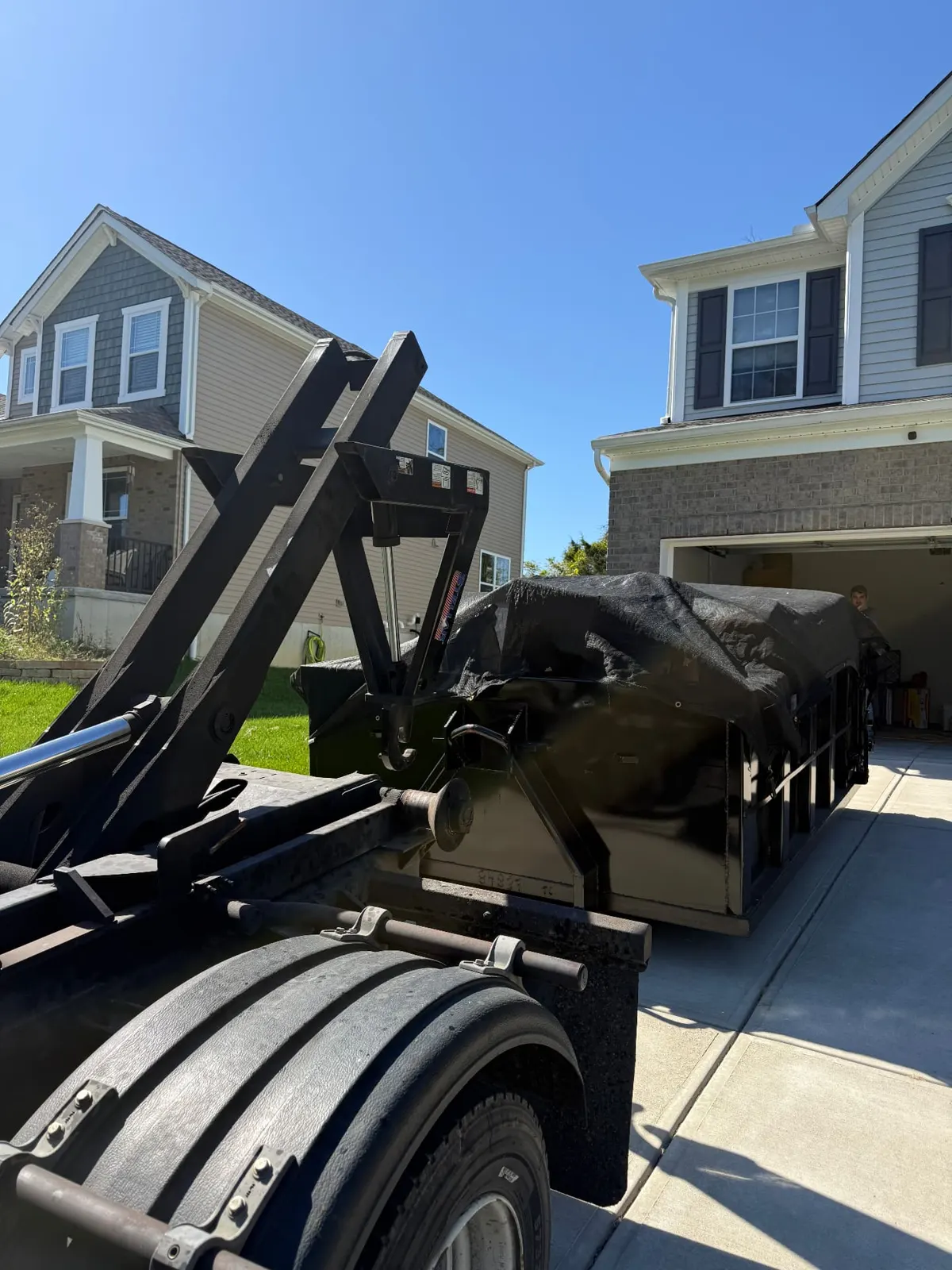 Clutter Cleanout tarped 10 yard dumpster with the roll-off truck on a residential driveway in Loveland, OH