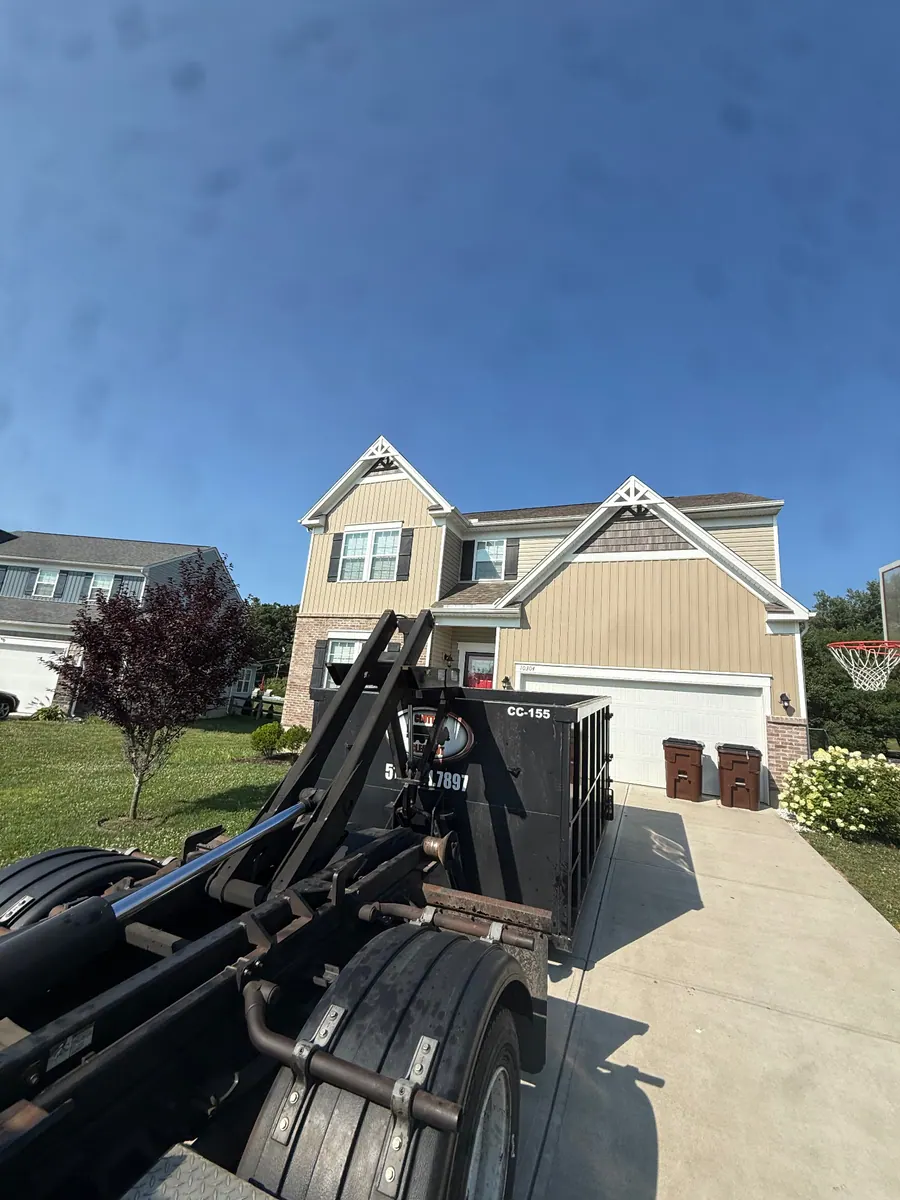 Clutter Cleanout roll-off truck delivering a 15 yard dumpster CC-155 to an Alexandria KY two-story home driveway