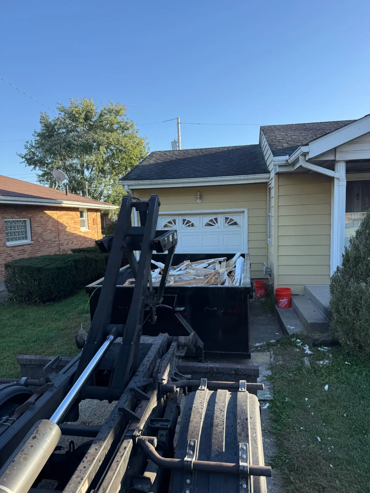 Clutter Cleanout 10 yard dumpster loaded with renovation debris beside the roll-off truck in a Cincinnati, OH driveway