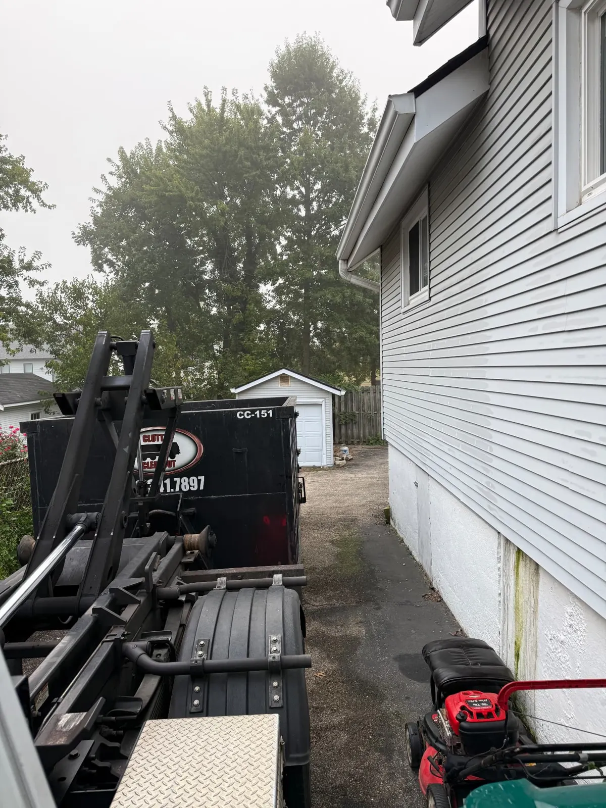 Clutter Cleanout 15 yard dumpster CC-151 with the roll-off truck in a narrow residential driveway in Norwood, OH