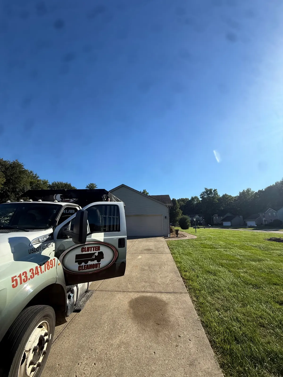 Clutter Cleanout truck delivering a 15 yard dumpster to a residential driveway in Milford, OH