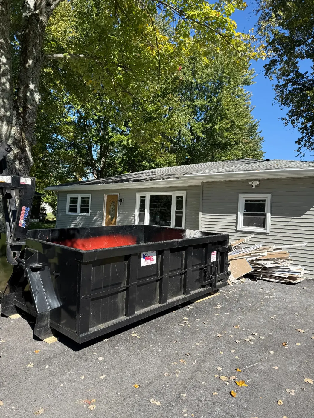 Clutter Cleanout 10 yard dumpster rental on a driveway beside renovation debris in Amelia, OH