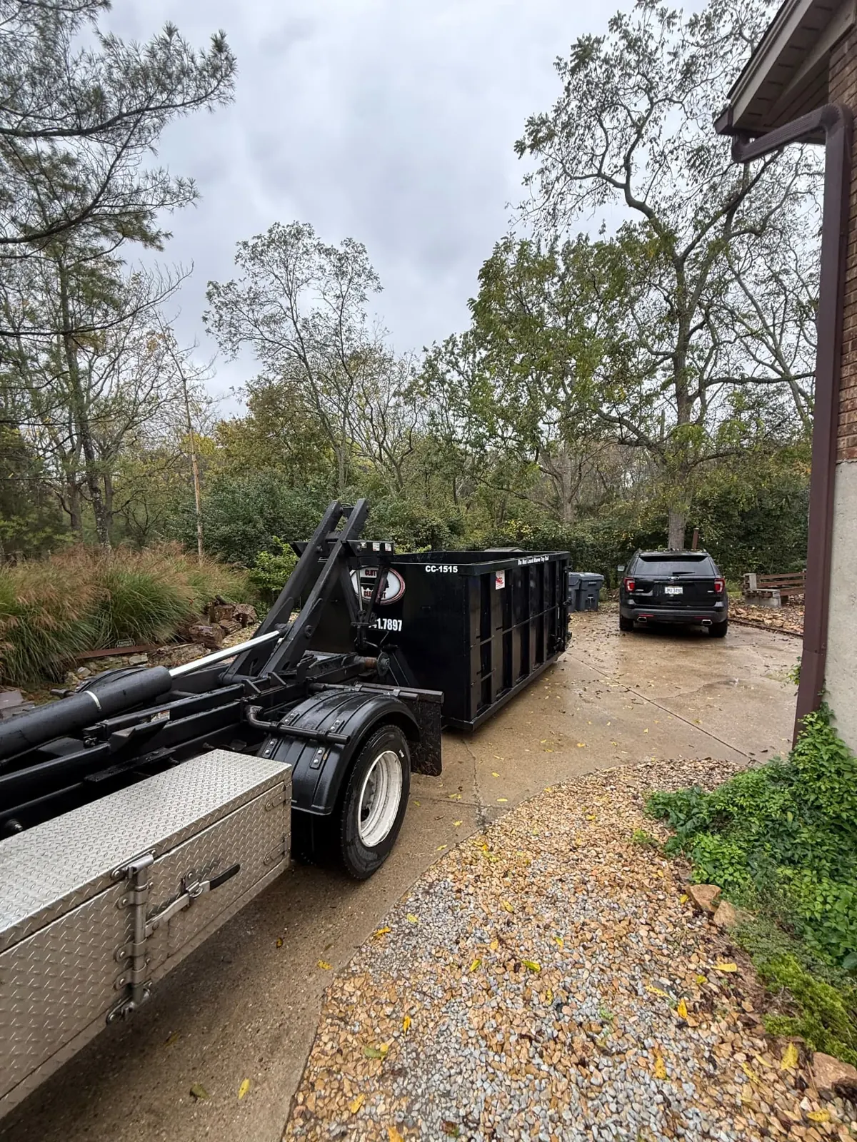Clutter Cleanout 15 yard dumpster CC-1515 with the roll-off truck on a wooded residential driveway in Cincinnati, OH