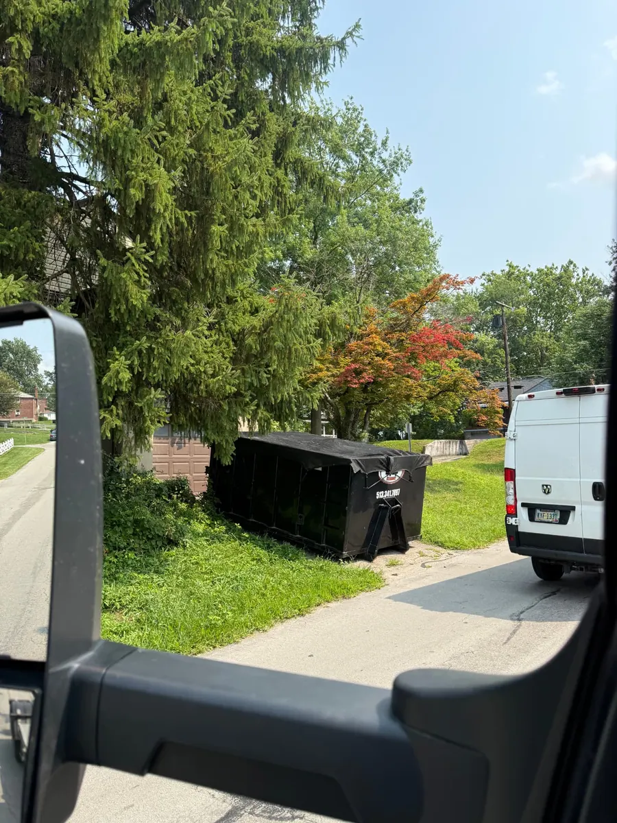 Tarped Clutter Cleanout 15 yard dumpster parked beside a garage in Oakley, Cincinnati OH