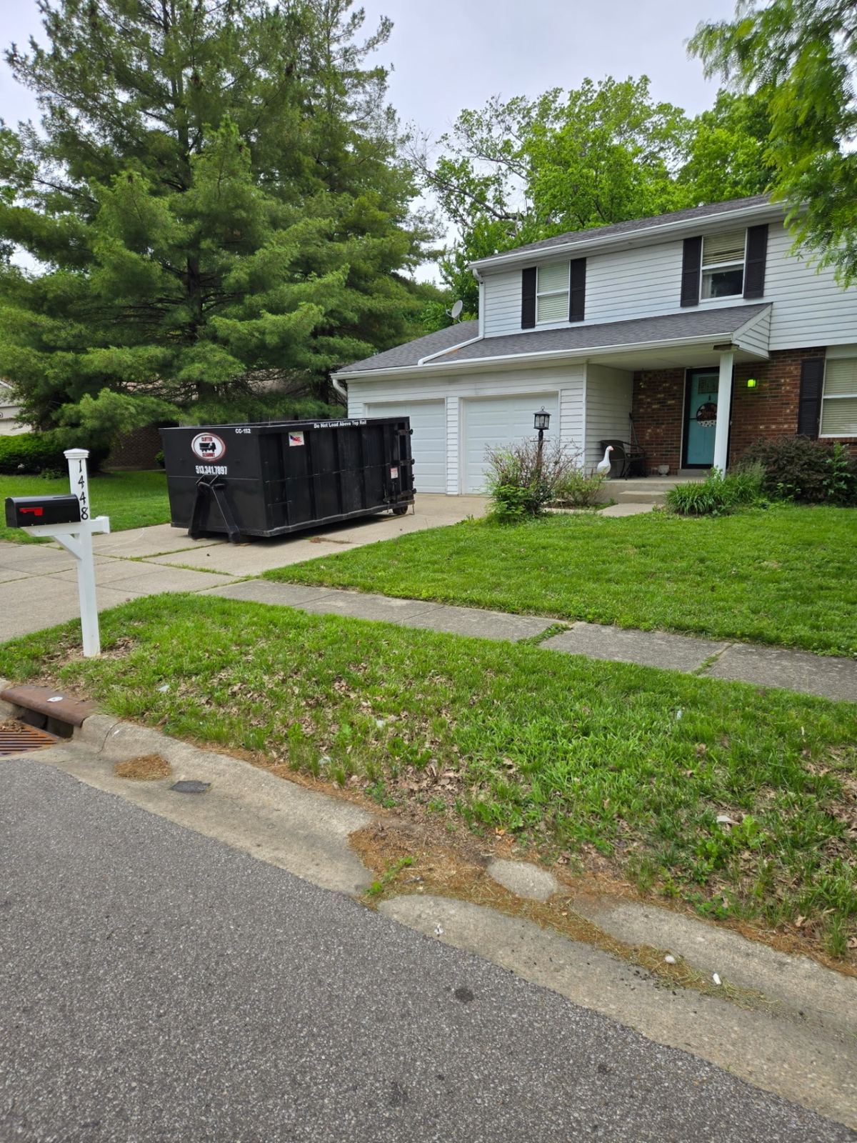 15-yard Clutter Cleanout dumpster CC-152 placed on a driveway in front of a two-story home in Amelia, OH