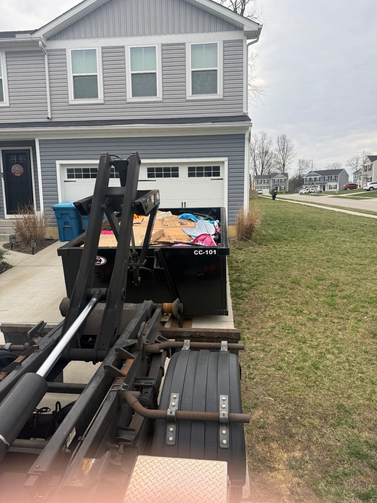 Clutter Cleanout truck picking up loaded dumpster CC-101 from an Amelia, OH home after a basement cleanout