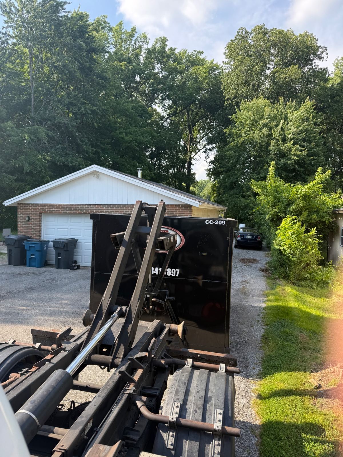 Clutter Cleanout 20 yard dumpster CC-209 being delivered to a Batavia OH driveway next to a brick garage