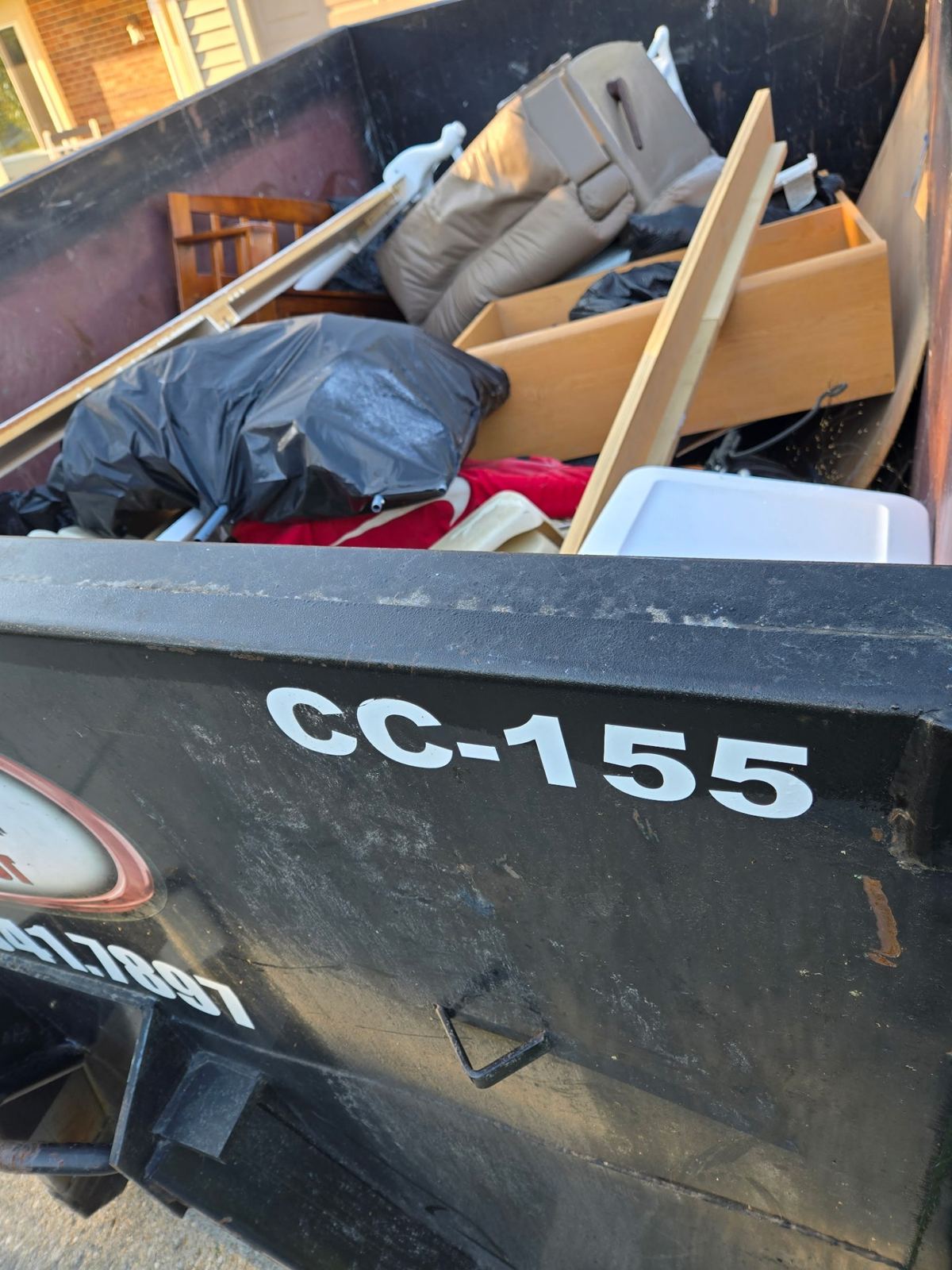 Loaded 15-yard dumpster CC-155 in Florence, KY filled with old furniture, drawers, bagged trash and household debris from a garage cleanout