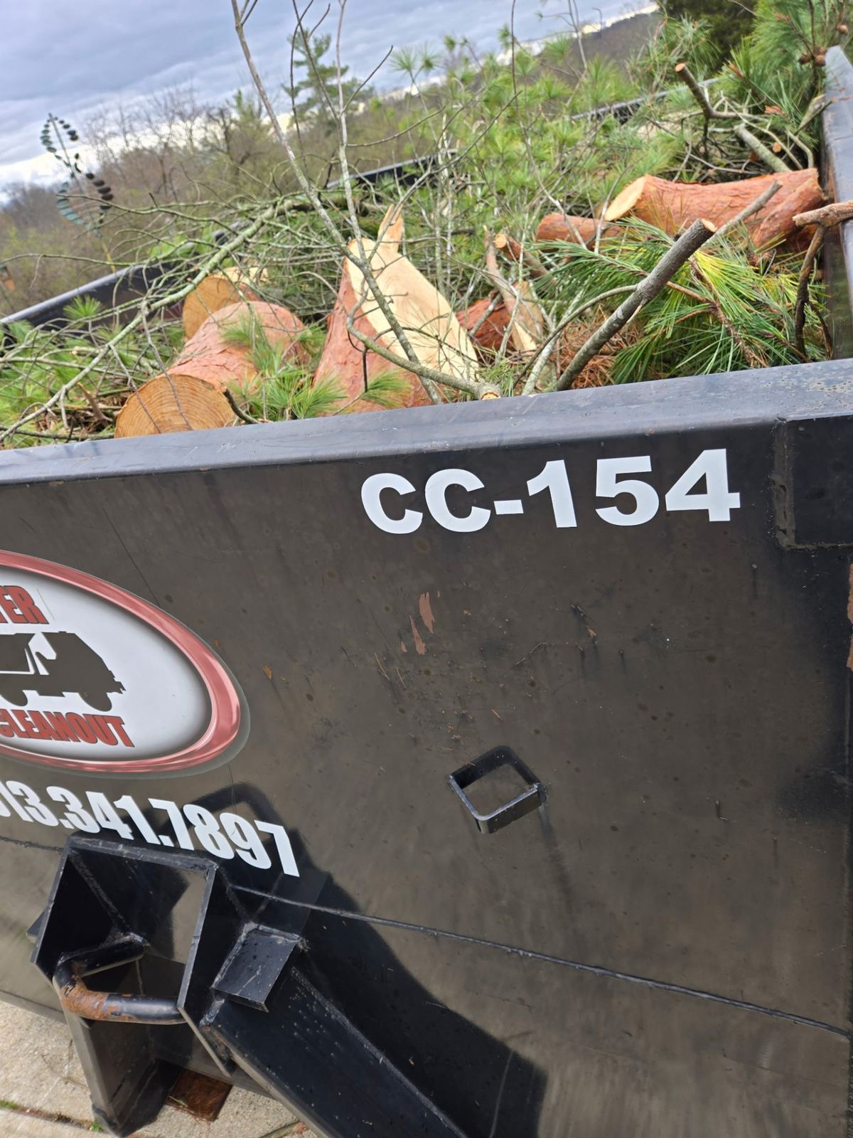 Close-up of Clutter Cleanout dumpster CC-154 loaded with tree debris and yard waste in Fort Mitchell, KY