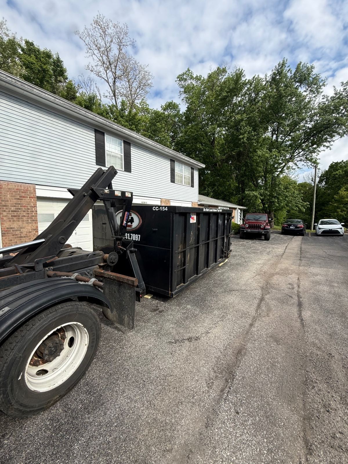 15 yard Clutter Cleanout dumpster CC-154 set on a townhome driveway in Independence KY between the garage and parked cars