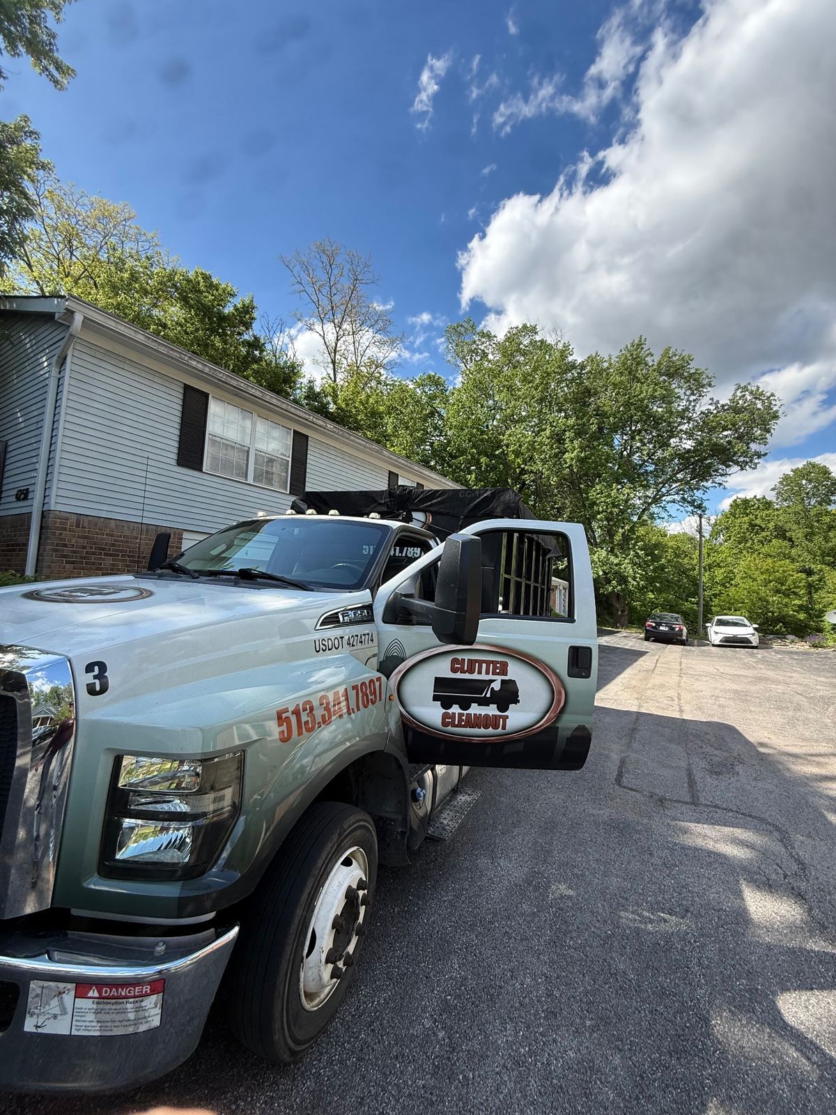 Clutter Cleanout roll-off truck #3 picking up a tarped dumpster from an Independence KY townhome