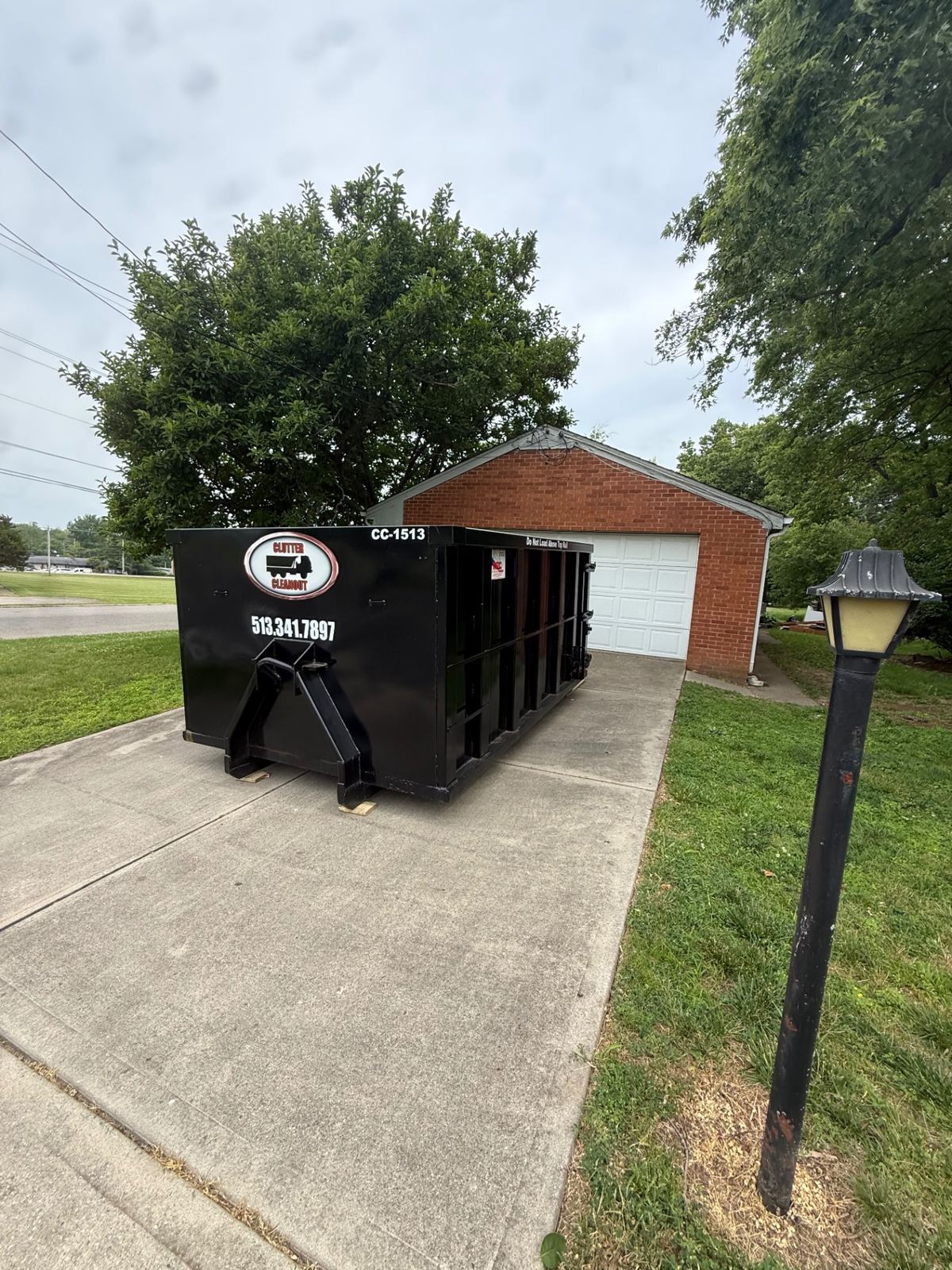Clutter Cleanout 15 yard dumpster CC-1513 placed on a Lebanon OH driveway in front of a brick garage for a home cleanout