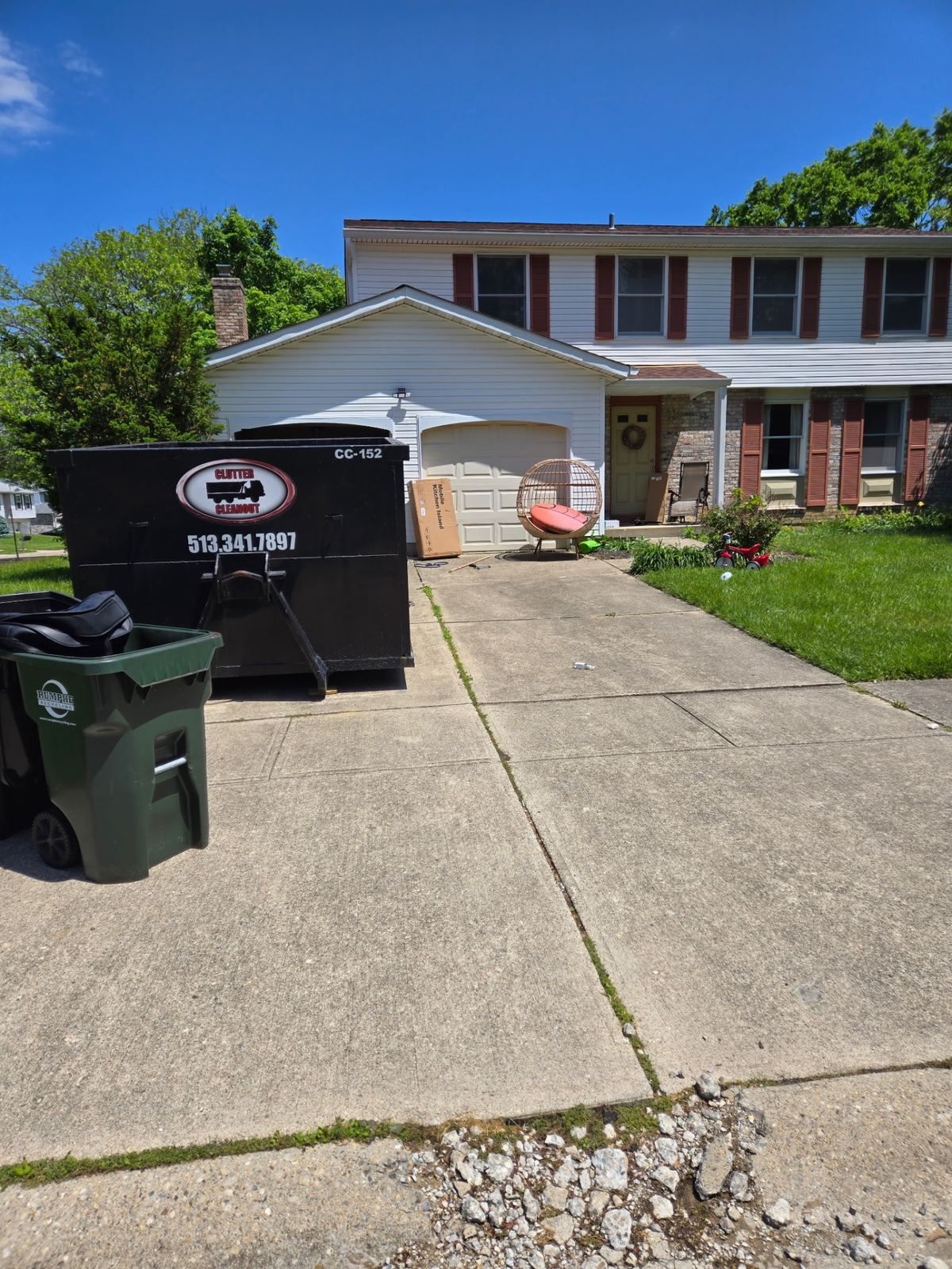 10-yard Clutter Cleanout dumpster CC-152 delivered to a Maineville OH driveway for a full garage cleanout with kitchen island and household items being loaded