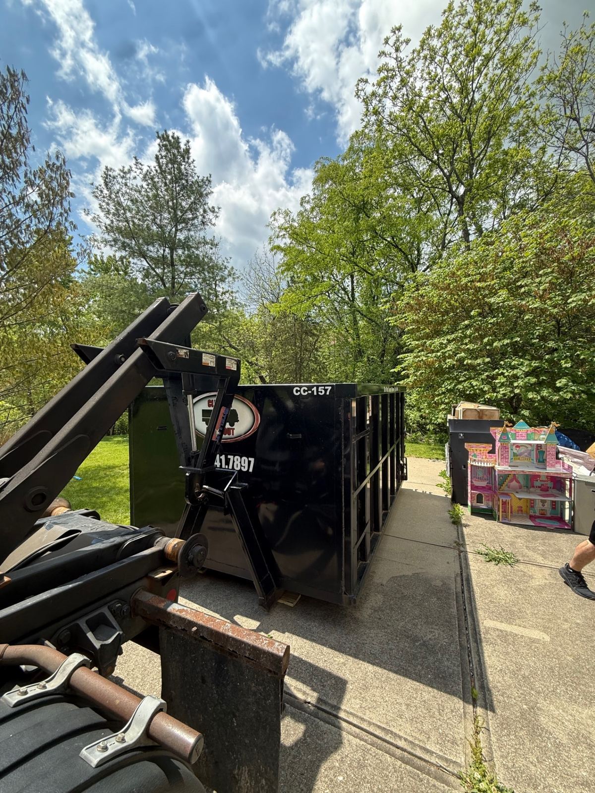 20 yard Clutter Cleanout dumpster CC-157 being delivered to a Villa Hills KY driveway next to a child's dollhouse and household debris